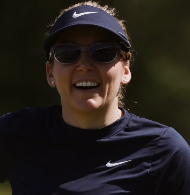 Hally Leadbetter, smiling on the course in a navy visor and sunglasses